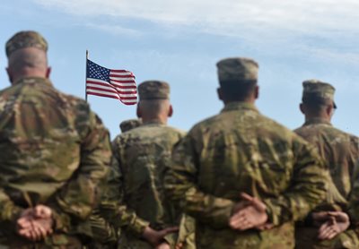 Soldiers at ease in front of flag
